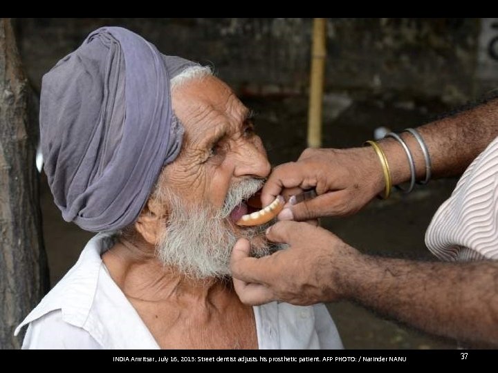 INDIA Amritsar, July 16, 2013: Street dentist adjusts his prosthetic patient. AFP PHOTO: /