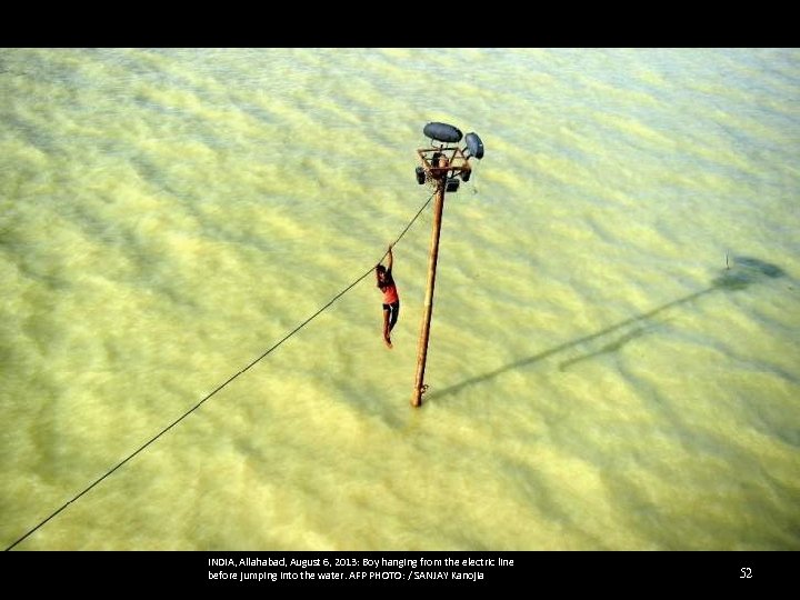 INDIA, Allahabad, August 6, 2013: Boy hanging from the electric line before jumping into