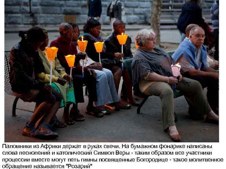 Паломники из Африки держат в руках свечи. На бумажном фонарике написаны слова песнопений и
