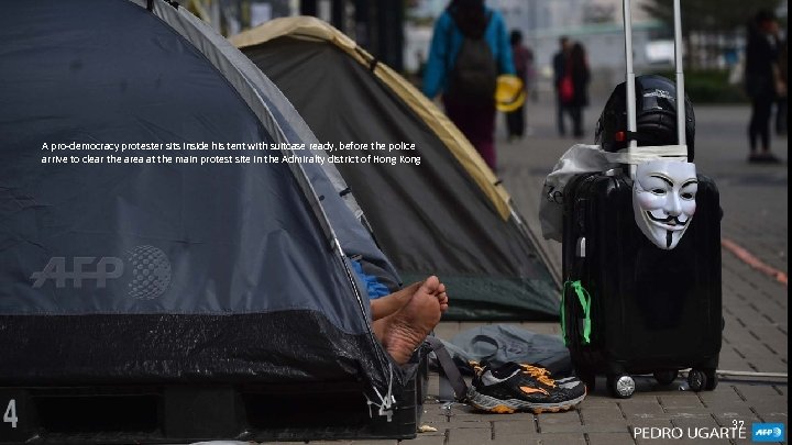 A pro-democracy protester sits inside his tent with suitcase ready, before the police arrive