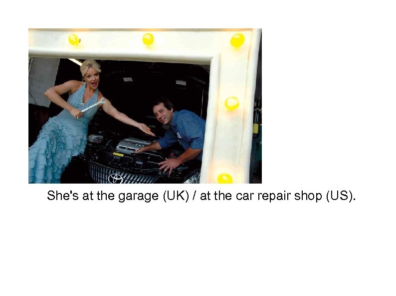 She's at the garage (UK) / at the car repair shop (US). 