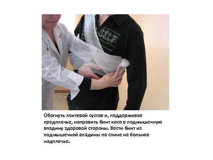 Обогнуть локтевой сустав и, поддерживая предплечье, направить бинт косо в подмышечную впадину здоровой стороны.