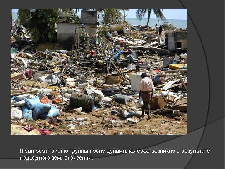 Люди осматривают руины после цунами, которое возникло в результате подводного землетрясения. 