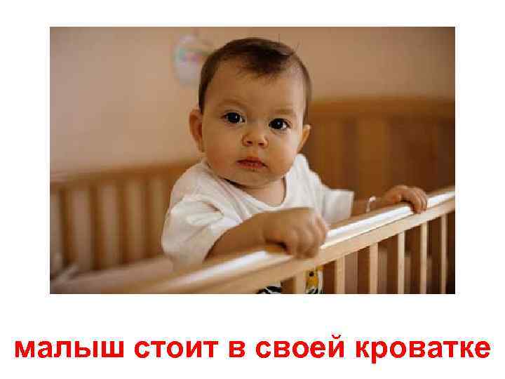 малыш стоит в своей кроватке 