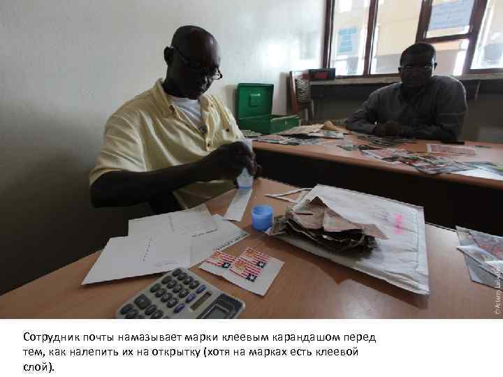 Сотрудник почты намазывает марки клеевым карандашом перед тем, как налепить их на открытку (хотя