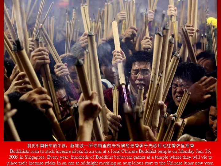 阴历中国新年的午夜，新加坡一所寺庙里前来祈福的进香者争先恐后地往香炉里插香 Buddhists rush to stick incense sticks in an urn at a local Chinese