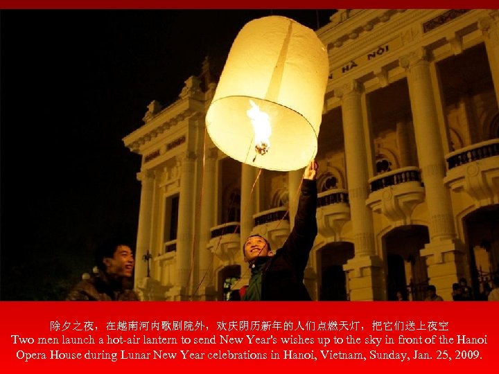 除夕之夜，在越南河内歌剧院外，欢庆阴历新年的人们点燃天灯，把它们送上夜空 Two men launch a hot-air lantern to send New Year's wishes up to