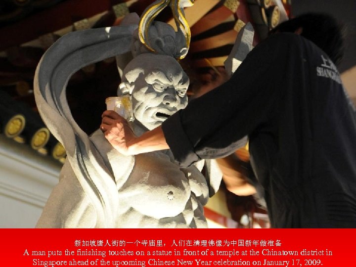 新加坡唐人街的一个寺庙里，人们在清理佛像为中国新年做准备 A man puts the finishing touches on a statue in front of a