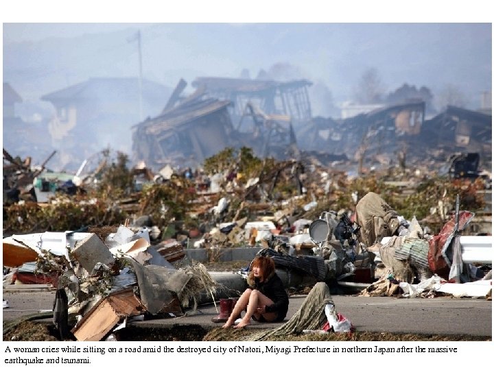 A woman cries while sitting on a road amid the destroyed city of Natori,