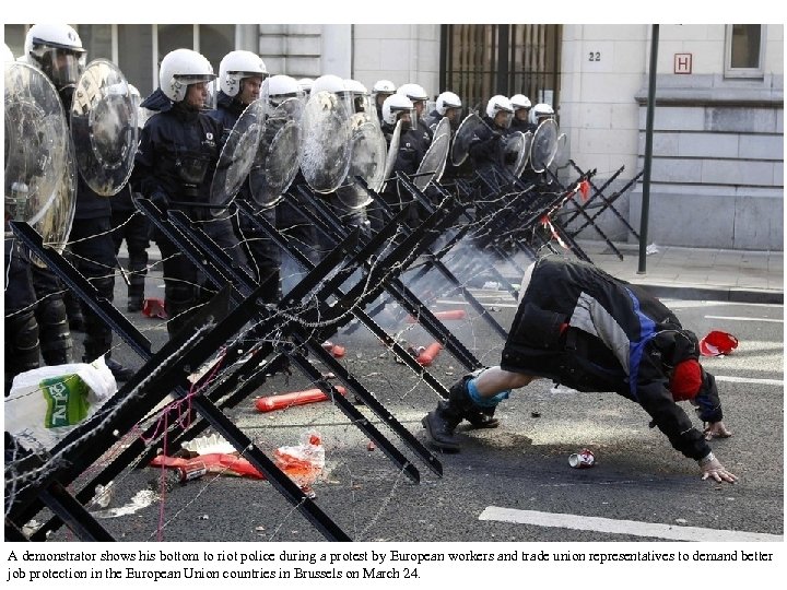 A demonstrator shows his bottom to riot police during a protest by European workers