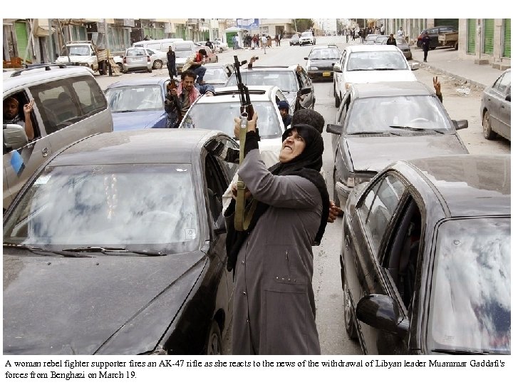 A woman rebel fighter supporter fires an AK-47 rifle as she reacts to the