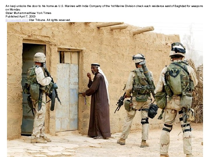 An Iraqi unlocks the door to his home as U. S. Marines with India