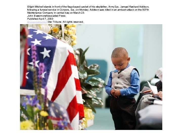 Ellijah Mitchell stands in front of the flag-draped casket of his stepfather, Army Spc.