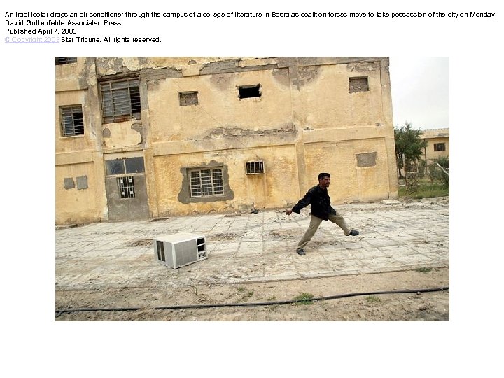 An Iraqi looter drags an air conditioner through the campus of a college of