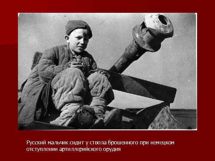 Русский мальчик сидит у ствола брошенного при немецком отступлении артиллерийского орудия 