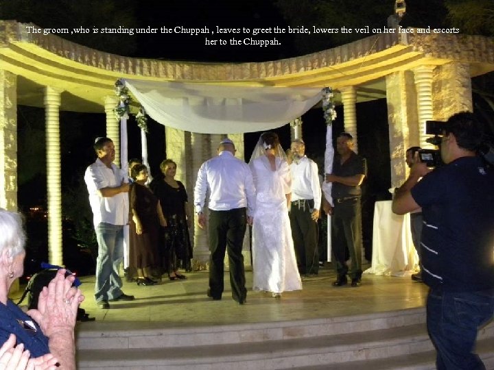 The groom , who is standing under the Chuppah , leaves to greet the