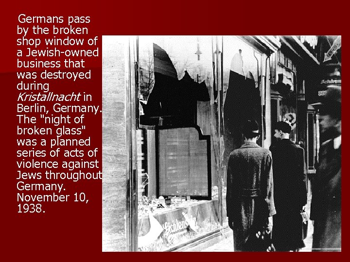  Germans pass by the broken shop window of a Jewish-owned business that was