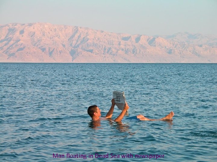 Man floating in Dead Sea with newspaper 