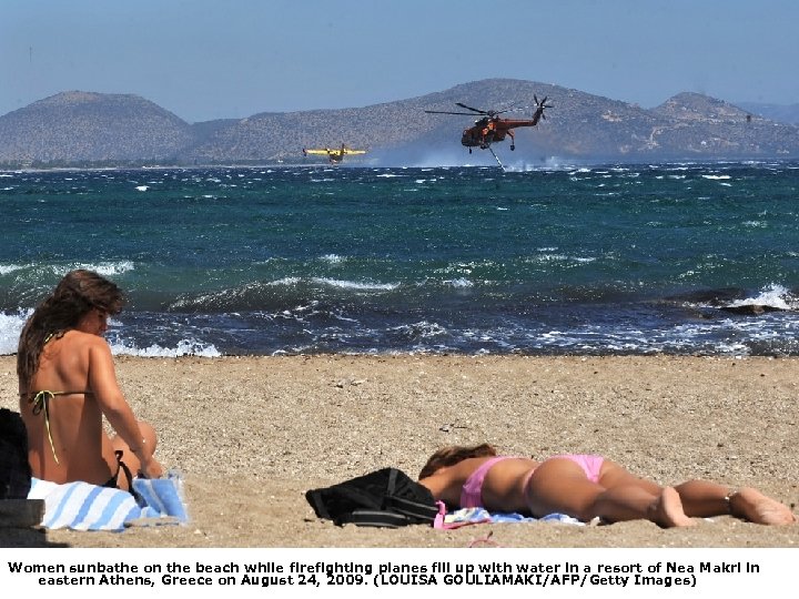 Women sunbathe on the beach while firefighting planes fill up with water in a