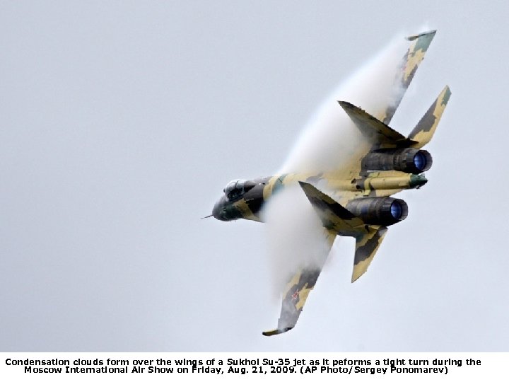 Condensation clouds form over the wings of a Sukhoi Su-35 jet as it peforms