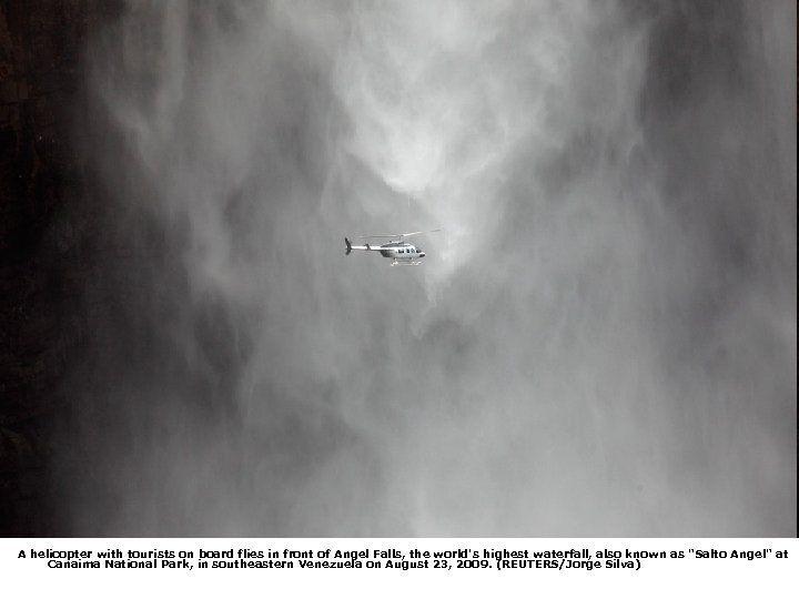 A helicopter with tourists on board flies in front of Angel Falls, the world's