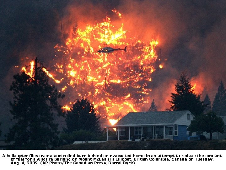 A helicopter flies over a controlled burn behind an evacuated home in an attempt