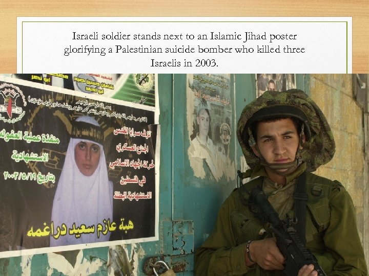 Israeli soldier stands next to an Islamic Jihad poster glorifying a Palestinian suicide bomber
