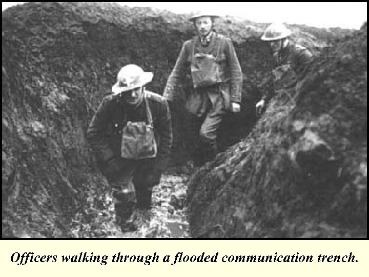 Officers walking through a flooded communication trench. 