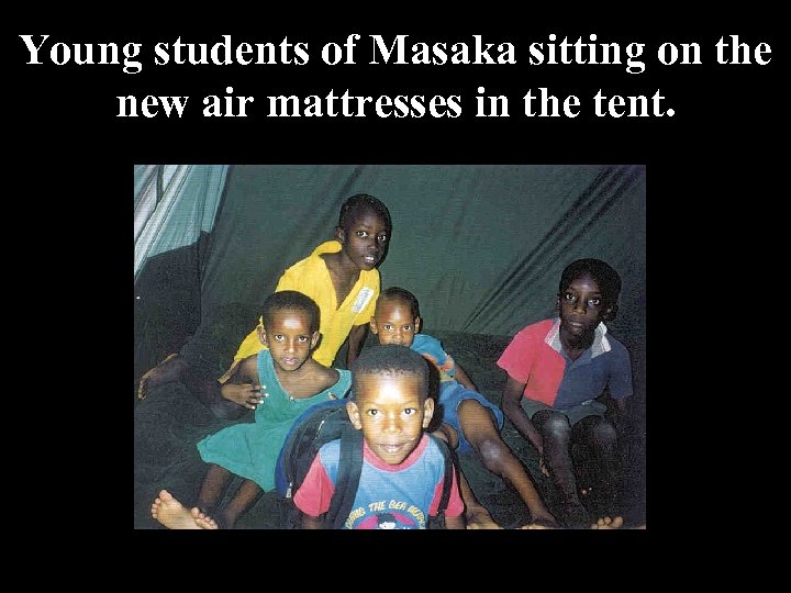 Young students of Masaka sitting on the new air mattresses in the tent. 